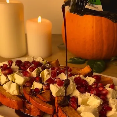 Pieczona dynia z fetą i granatem, polana olejem z pestek dyni.